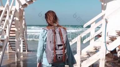 女孩走在白色楼梯到阳光明媚的海岸。 自由。 头发随风<strong>飘动</strong>。 <strong>带</strong>背包的女人在海滩上。 慢动作。